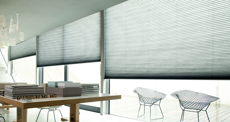Decorquip grey pleated blinds partially lowered across large windows in a modern interior