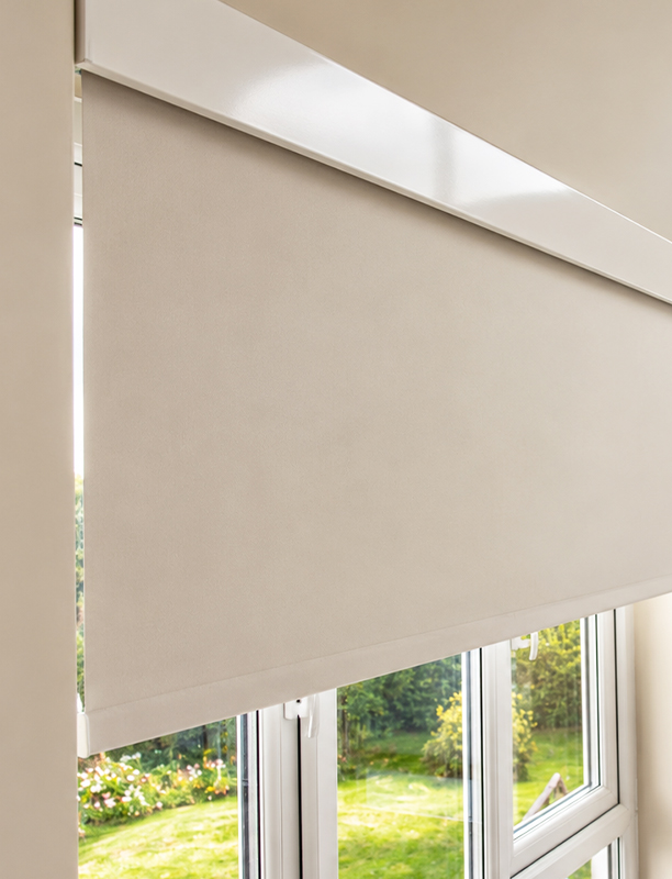 Decorquip motorised cream roller blind with white Capital Fascia partially lowered over a white-framed window in an interior setting