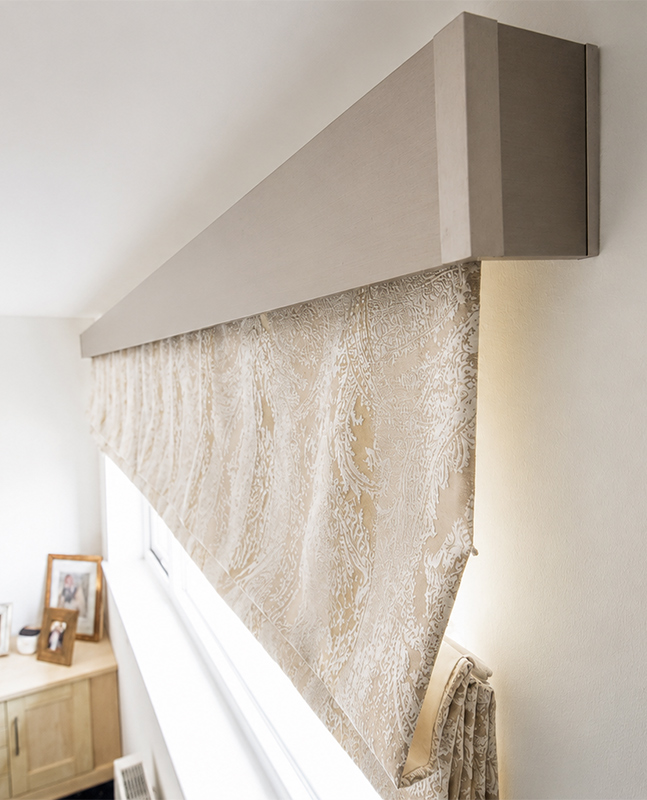 Decorquip patterned beige Roman blind partially lowered beneath a Capital fascia in a bedroom